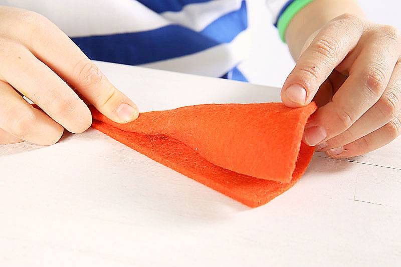 Schneiden Sie aus dem orangefarbenen Filz ungef&auml;hr einen Achtelkreis. Drehen Sie ihn zu einer kleinen T&uuml;te zusammen.