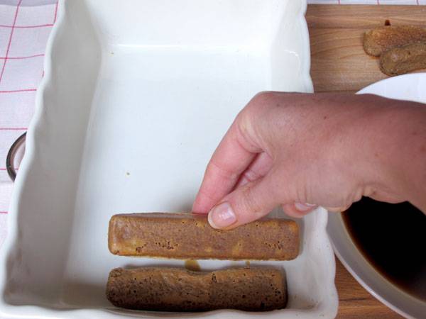 Tunken Sie die L&ouml;ffelbiskuit in den Kaffee und legen sie in die Form